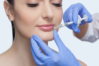 Doktor kozmetik uzmanı güzellik salonunda güzel bir kadının dudak büyütme prosedürünü yapıyor. Kozmetik cilt bakımı..