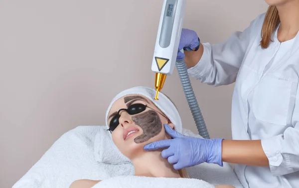 Carbon face peeling procedure in a beauty salon. Hardware cosmetology treatment.