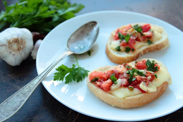 Křupavá bruschetta s rajčaty, sýrem a bylinkami — Stock fotografie