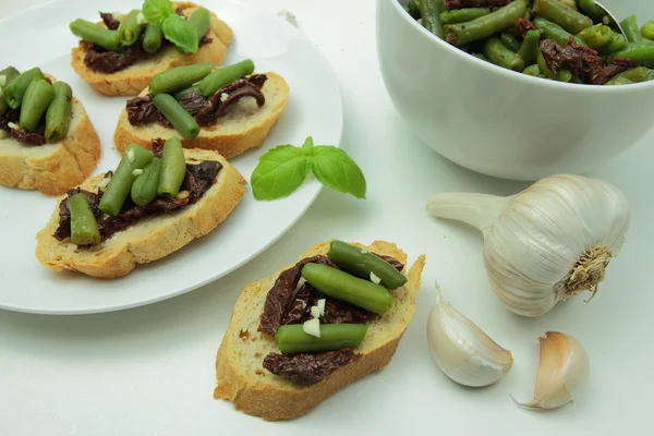 Bruschettas with dried tomatoes and green bean — Stock Photo, Image