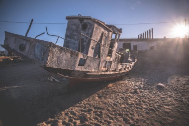 Paslı, donmuş eski bir gemi kışın kıyıda duruyor.