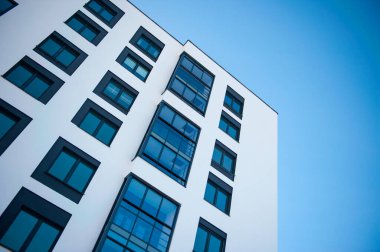 Yeni binanın pencereleri ve balkonları mavi gökyüzüne karşı.