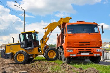 Traktör toprağı çöp kamyonuna yüklüyor. Yol onarımları.