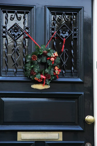 Clásica corona de Navidad con decoraciones en una puerta —  Fotos de Stock