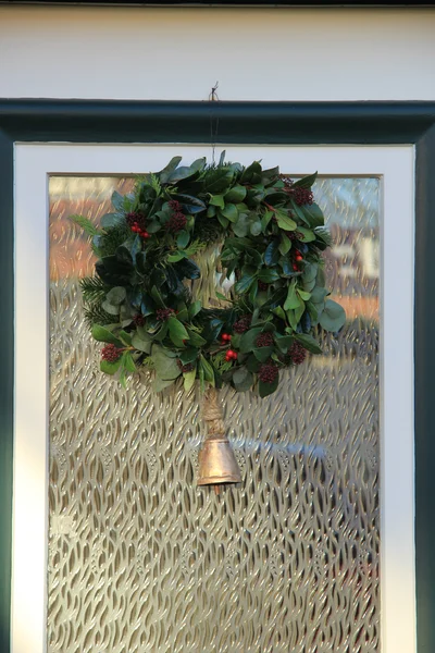 Clásica corona de Navidad con decoraciones en una puerta —  Fotos de Stock