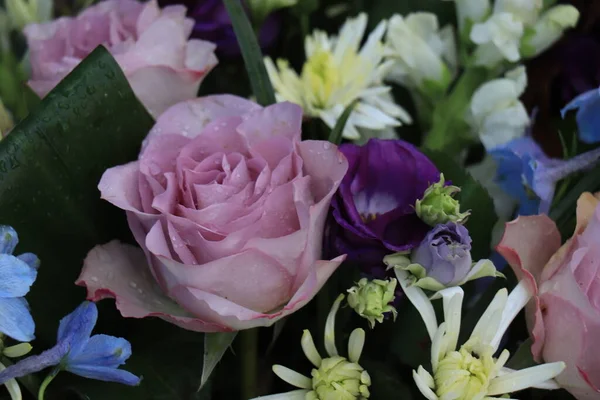 Purple and blue flower arrangement for a wedding: purple roses and blue larkspur