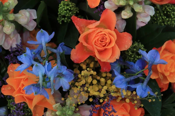 婚礼上的橙色和蓝色花朵安排 橙色玫瑰和蓝色云雀 图库照片