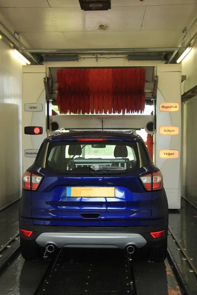一辆蓝色Suv在自动洗车 机器上的文字 荷兰语的程序项目 — 图库照片