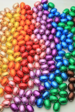 Bir grup folyo sarılıp gökkuşağı renklerine bürünmüş çikolatalı yumurta.