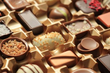 Bir hediye kutusunda çeşitli şekillerde ve tatlarda lüks çikolatalar.