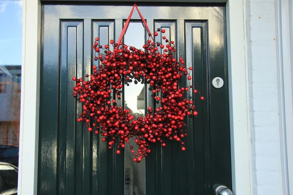 Grinalda de Natal de baga com decorações em uma porta — Fotografia de Stock