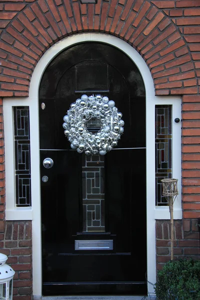 Silver christmas wreath with decorations on a door — Stock Photo, Image