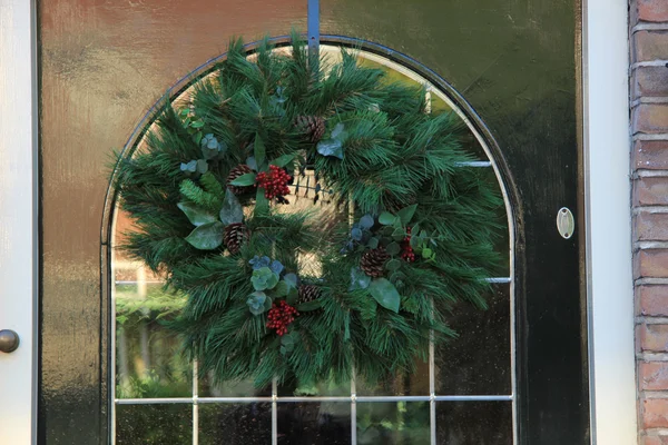 Clásica corona de Navidad con decoraciones en una puerta —  Fotos de Stock