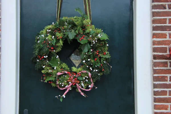 Clásica corona de Navidad con decoraciones en una puerta —  Fotos de Stock