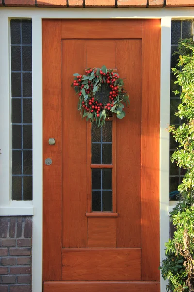 Berry christmas wreath with decorations on a door — Stock Photo, Image