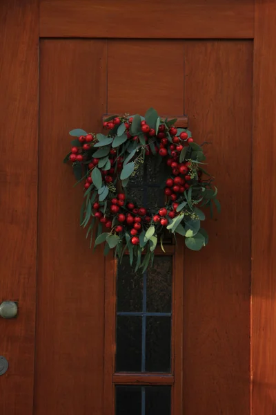 Grinalda de Natal de baga com decorações em uma porta — Fotografia de Stock