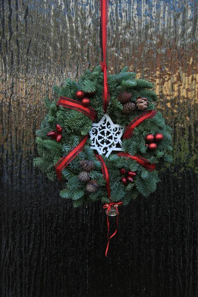 Clásica corona de Navidad con decoraciones en una puerta — Foto de Stock