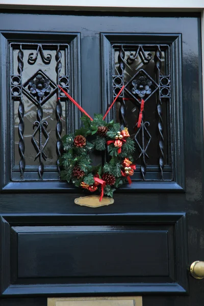 Classica corona di Natale con decorazioni su una porta — Foto Stock