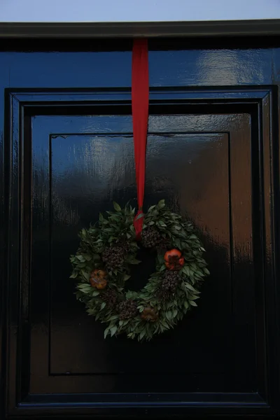 Clásica corona de Navidad con decoraciones en una puerta —  Fotos de Stock