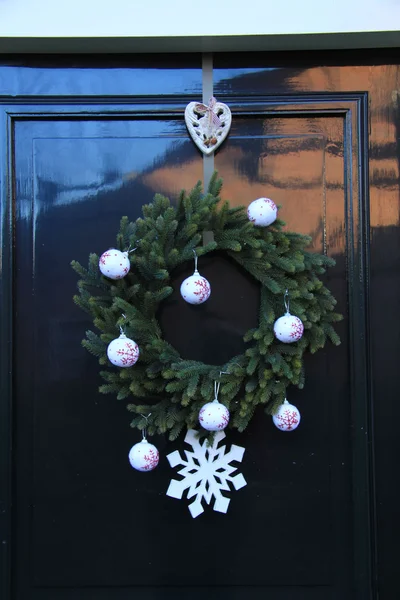 Clásica corona de Navidad con decoraciones en una puerta —  Fotos de Stock