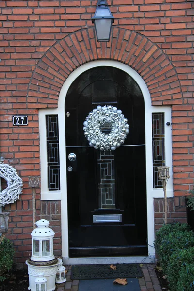 Silver christmas wreath with decorations on a door — Stock Photo, Image