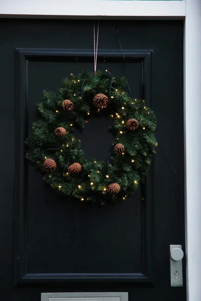 Clásica corona de Navidad con decoraciones en una puerta —  Fotos de Stock