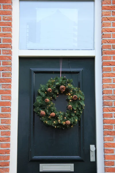 Clásica corona de Navidad con decoraciones en una puerta —  Fotos de Stock