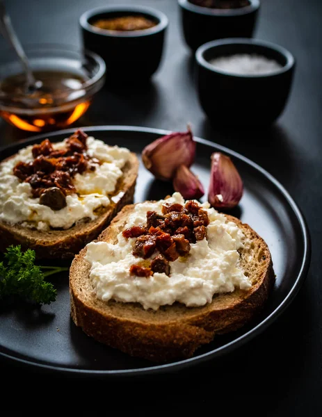 Breakfast - cottage cheese, bread, bruschetta and vegetables on black wooden table