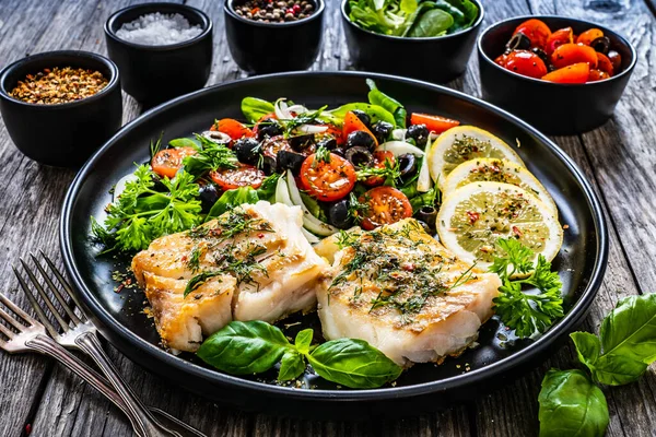 魚料理 木製のテーブルの上に新鮮な野菜サラダと揚げタラフィレ — ストック写真