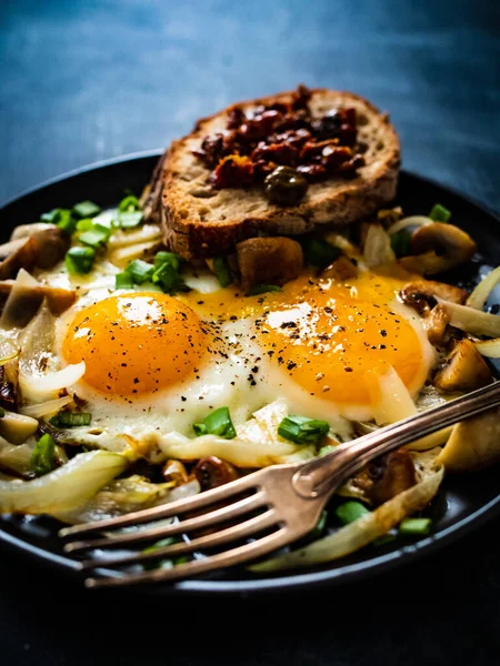 欧洲大陆的早餐 阳光明媚的一面 白蘑菇上的鸡蛋 黑桌上的洋葱和番茄酱 — 图库照片