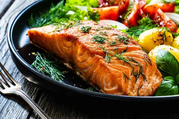 Gefrituurde Zalmsteak Met Gebraden Aardappelen Groentesalade Geserveerd Zwarte Plaat Houten — Stockfoto