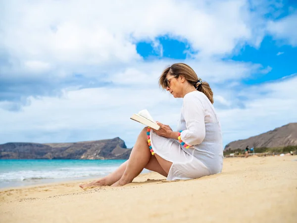 ビーチ読書本に座っている女性 — ストック写真