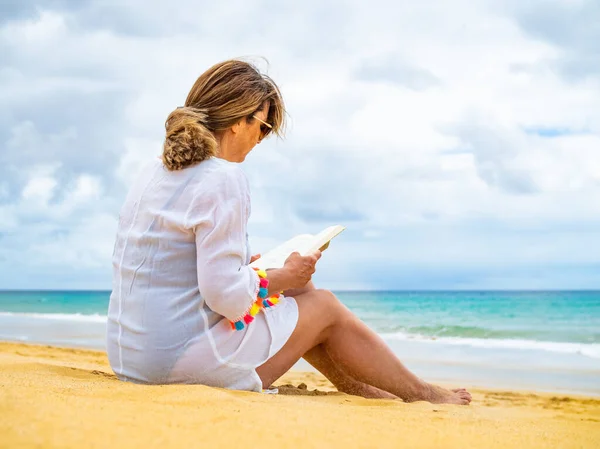 坐在沙滩上看书的女人 — 图库照片