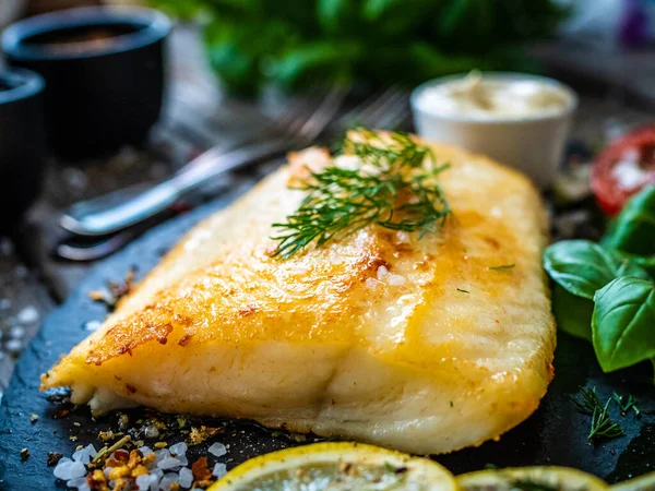 魚料理 木製のテーブルの上に石板に提供されるジャガイモと野菜サラダと揚げタラフィレ — ストック写真