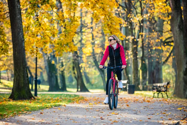 都市自転車 都会の公園で自転車に乗る中年女性 — ストック写真