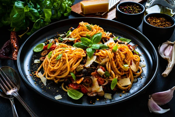 トマトソースとスパゲッティプッタネスカ アンチョビ 木製のテーブルの上のケッパーとオリーブ — ストック写真