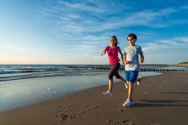 Adolescente et garçon courir sur la plage — Photo