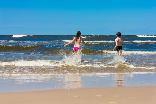 Mädchen und Junge springen und rennen am Strand — Stockfoto