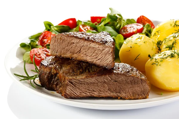 Steaks grillés, pommes de terre et salade de légumes — Photo