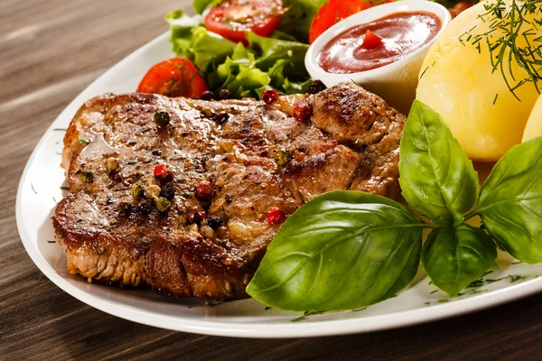 Grilled steaks, French fries and vegetables — Stock Photo, Image