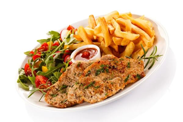 Franse frietjes, gebakken varkensvlees en groenten — Stockfoto