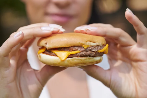 Cheeseburger v ženských rukou — Stock fotografie