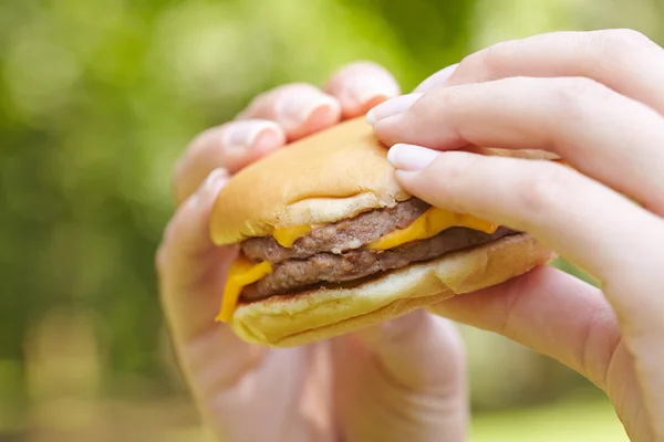 Cheeseburger v ženských rukou — Stock fotografie