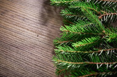 Tahta arka planda Noel ağacı dalları olan bir Noel kartı.
