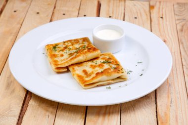 Beyaz tabakta ekşi kremalı krep, yakın görüş.