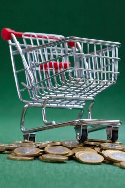 Alışveriş sepetinin altındaki bozuk paralar, yeşil arka plan
