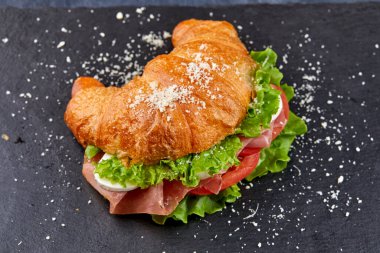 Koyu arka planda jambon ve sebzeli kruvasan, yakın görüş. 