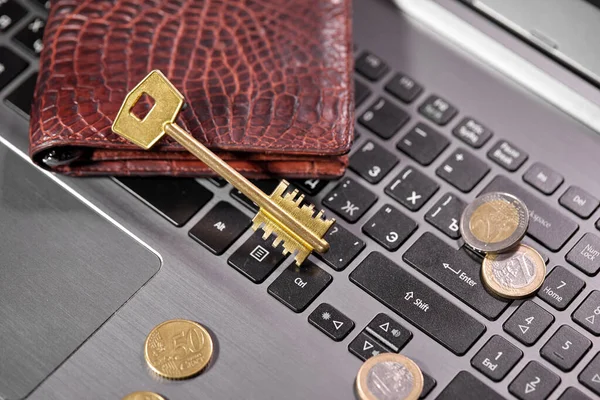 money coins with purse and key on computer laptop, close view