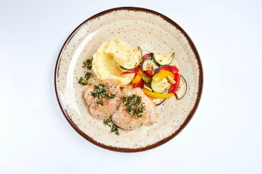 Beyaz tabakta patates püresi ve sebzeli tavuk, yakın görüş. 