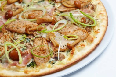 Beyaz tabakta etli ve mantarlı pizza, yakın görüş. 